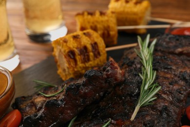 Photo of Delicious grilled ribs and corn on table, closeup view