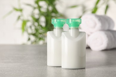 Photo of Mini bottles of cosmetic products on light grey table against blurred background. Space for text