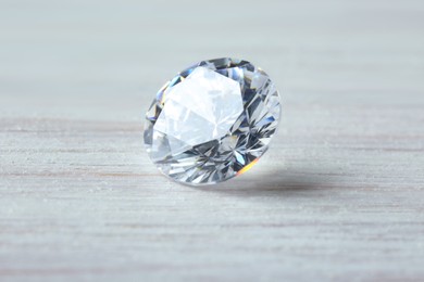 Photo of Beautiful shiny diamond on light wooden table