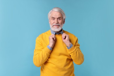 Portrait of stylish grandpa on light blue background