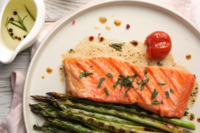 Photo of Tasty grilled salmon with tomato, asparagus and spices on table, flat lay