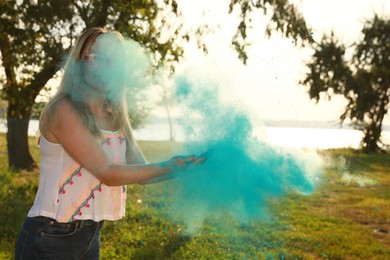 Young woman with blue powder dye outdoors. Holi festival celebration