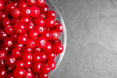 Photo of Fresh cranberry in bowl on dark grey table, closeup. Space for text