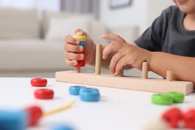 Photo of Motor skills development. Little boy playing with stacking and counting game at table indoors, closeup