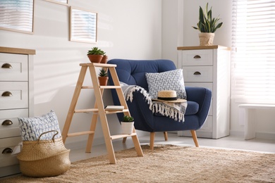 Photo of Stylish living room interior with wooden ladder and comfortable armchair