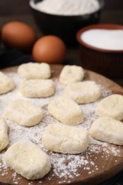 Photo of Making lazy dumplings. Wooden board with cut dough and ingredients on table, closeup