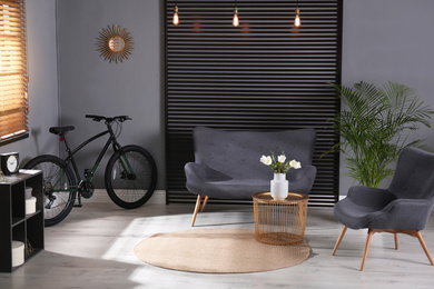 Photo of Modern bicycle and comfortable sofa in stylish living room interior