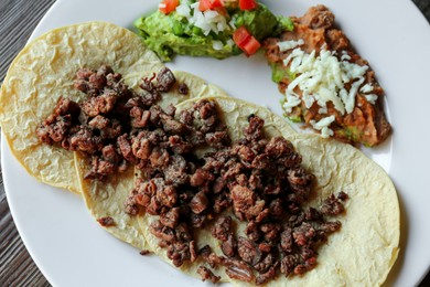 Photo of Plate with delicious tacos served on wooden table, top view