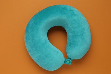 Photo of Turquoise travel pillow on orange background, top view