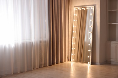 Photo of Modern mirror with light bulbs in makeup room