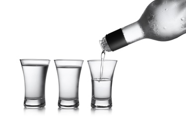 Photo of Pouring cold vodka into shot glass on white background