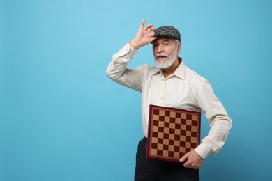 Photo of Man with chessboard on light blue background. Space for text