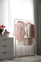 Photo of Rack with stylish women's clothes indoors. Interior design
