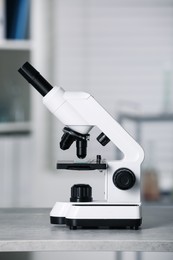 Photo of Modern medical microscope on grey table in laboratory