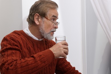 Photo of Upset senior man with glass of water at home Loneliness concept