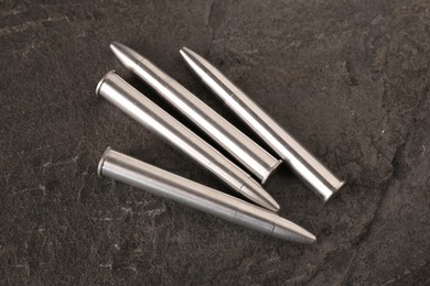 Photo of Metal bullets on dark textured table, above view