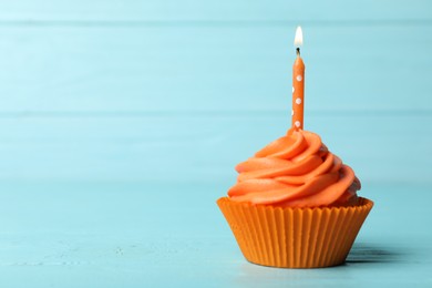 Photo of Delicious birthday cupcake with cream and burning candle on blue wooden background. Space for text
