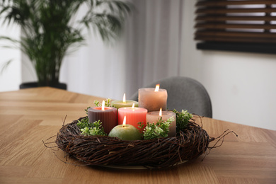 Photo of Beautiful burning candles on wooden table indoors