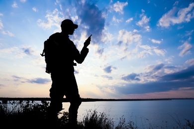 Photo of Soldier with portable radio transmitter outdoors. Military service