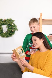 Photo of Happy woman receiving greeting card from her son at home