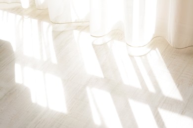 Photo of Curtain over sunlit wooden floor in morning