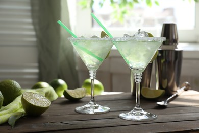 Photo of Delicious Margarita cocktail in glasses and lime on wooden table