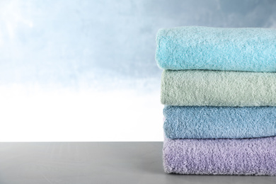 Photo of Stack of clean bath towels on grey table. Space for text