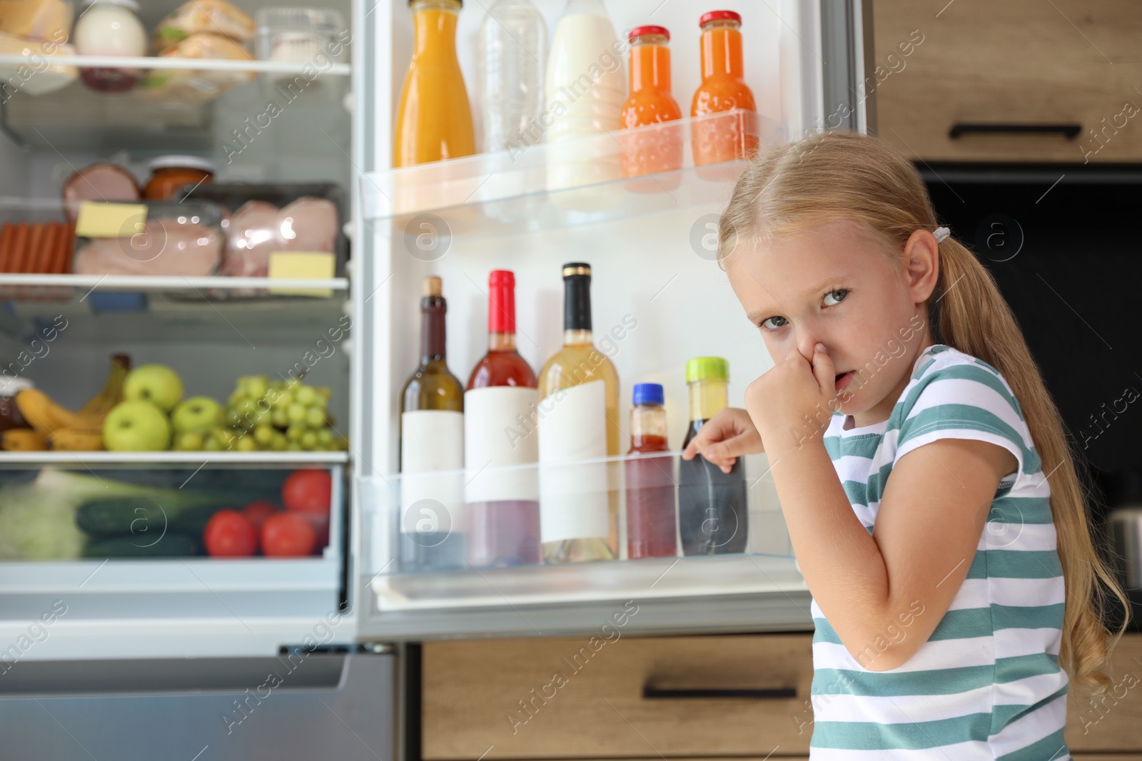Photo of Girl feeling bad smell from stale products in refrigerator at home