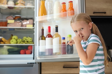 Photo of Girl feeling bad smell from stale products in refrigerator at home