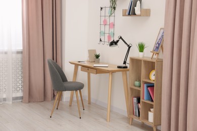 Photo of Stylish workplace with wooden desk, chair and lamp in room. Interior design