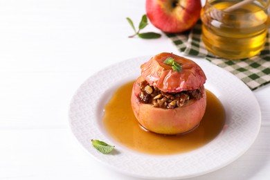 Photo of Tasty baked apple with nuts, honey and mint on white wooden table, closeup