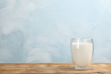 Photo of Glass with fresh milk on table against color background. Space for text