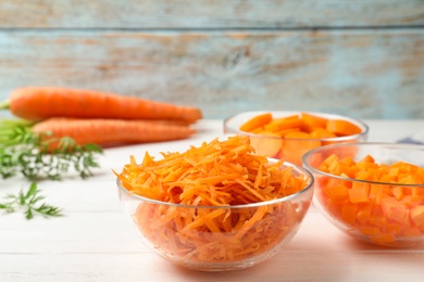 Photo of Bowls of differently cut carrots on white table