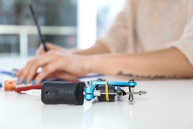 Photo of Professional tattoo machine and blurred master on background