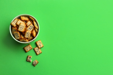 Photo of Delicious crackers in bowl on light green background, flat lay. Space for text