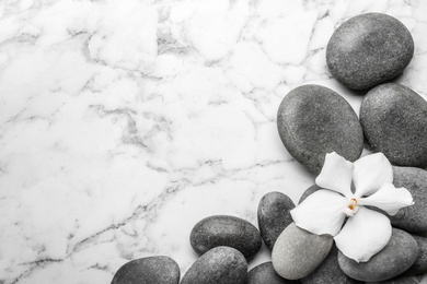 Stones and orchid flower on marble background, top view with space for text. Zen lifestyle
