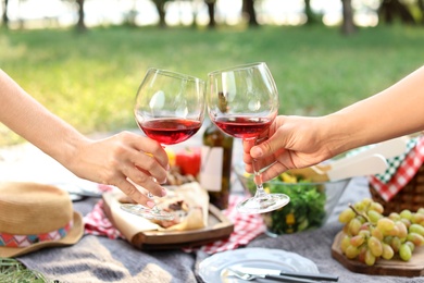 Photo of Happy couple drinking wine in park, closeup. Summer picnic