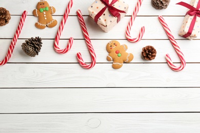 Photo of Flat lay composition with candy canes and Christmas cookies on white wooden table. Space for text