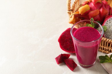 Photo of Delicious pitahaya smoothie and fresh fruits on light grey table, space for text