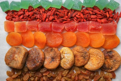 Photo of Different tasty dried fruits on paper, flat lay