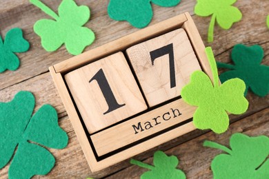 Photo of St. Patrick's day - 17th of March. Block calendar and felt clover leaves on wooden background, above view