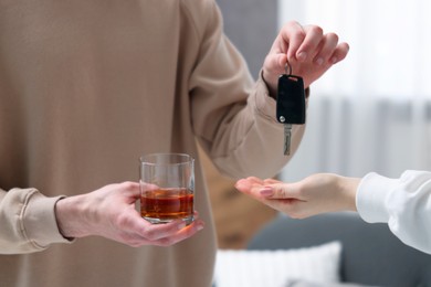 Photo of Man with glass of alcoholic drink giving car key to woman, closeup. Don't drink and drive concept