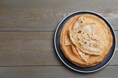 Photo of Stack of delicious crepes on grey wooden table, top view. Space for text