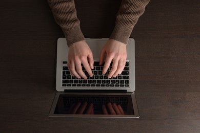 Man working with laptop at wooden table, top view