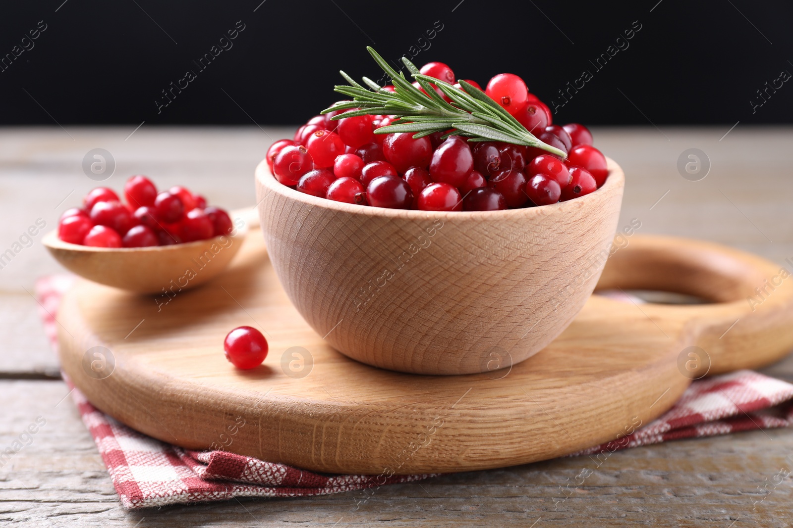 Photo of Fresh ripe cranberries and rosemary on wooden table