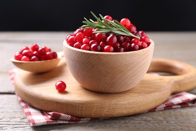 Photo of Fresh ripe cranberries and rosemary on wooden table