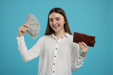 Photo of Happy woman with dollar banknotes and wallet on light blue background