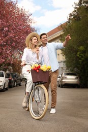 Photo of Lovely couple with bicycle and flowers on city street