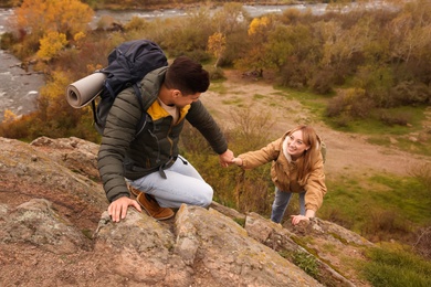 Photo of Couple of hikers with backpacks climbing up mountains