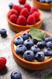 Photo of Tartlet with fresh blueberries on light grey table, closeup. Delicious dessert